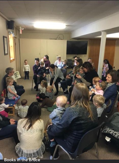 Children and their caregivers enjoy a story being read aloud at a Books in the Bruce program. This project was made possible through the